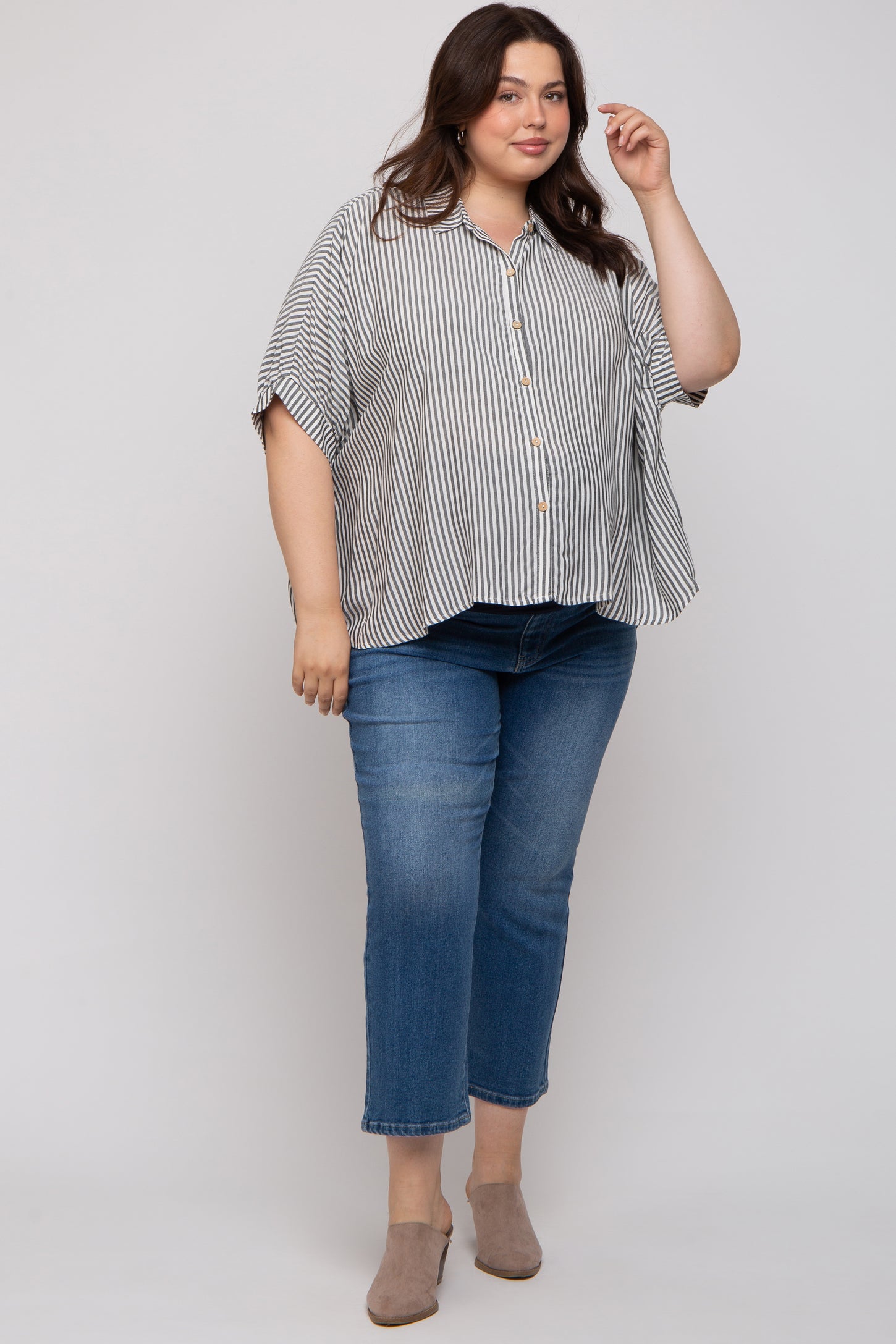 woman wearing a striped short sleeve button-up maternity plus top paired with blue jeans