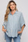 woman wearing a light blue and white striped maternity shirt with a loose fit and short sleeves, hands in pockets