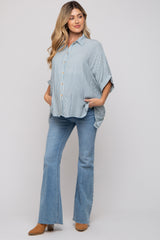 woman wearing a striped blue maternity top with button details and flared jeans, showcasing her baby bump