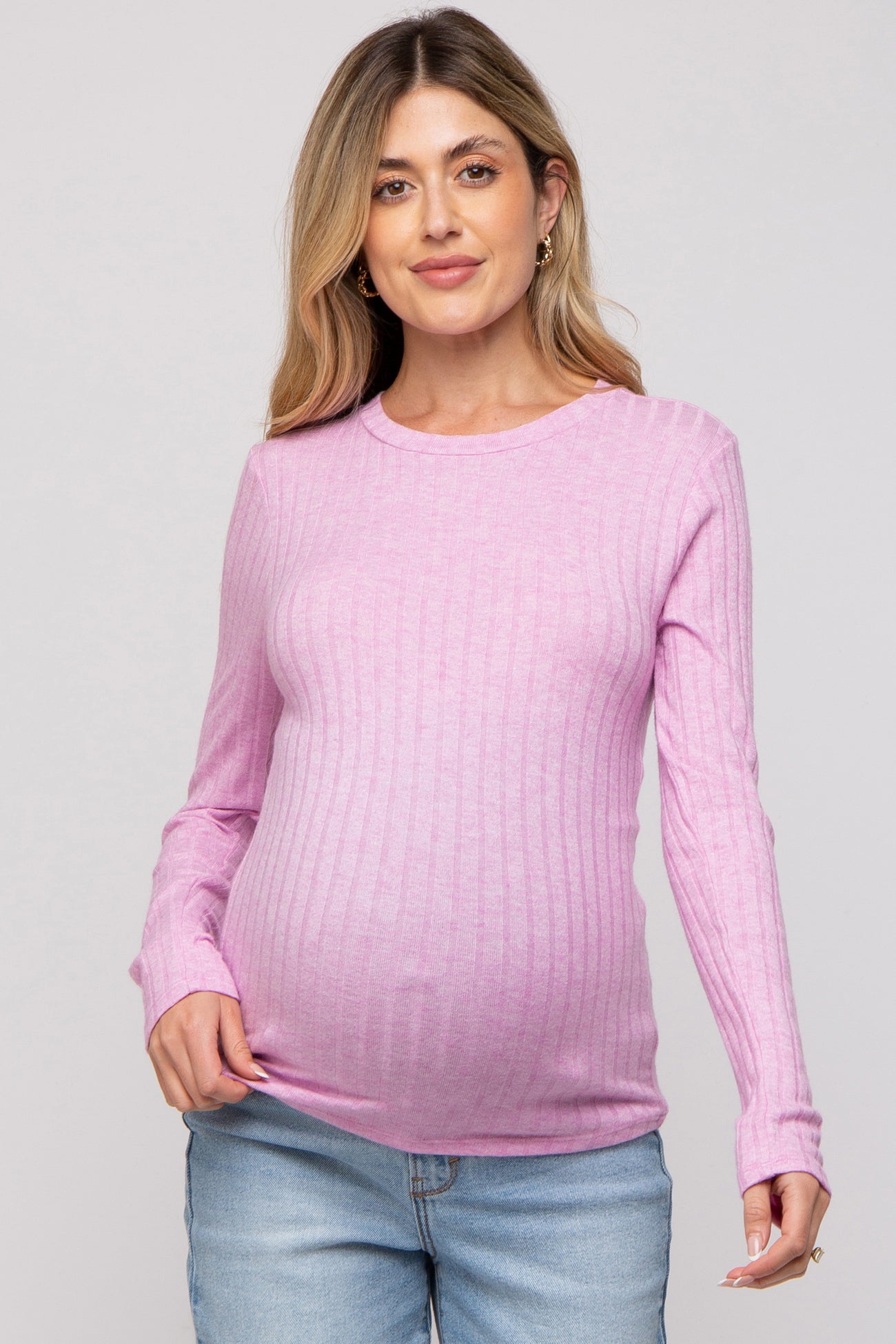 woman wearing a soft pink ribbed long sleeve maternity top and showing her baby bump