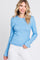 woman wearing a light blue long sleeve ribbed top and smiling at the camera