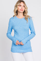 woman wearing a light blue long sleeve ribbed top with a rounded neckline and fitted silhouette
