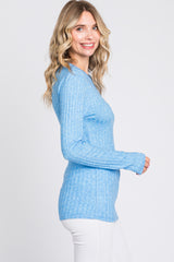 woman wearing a light blue ribbed long sleeve top and smiling to the side