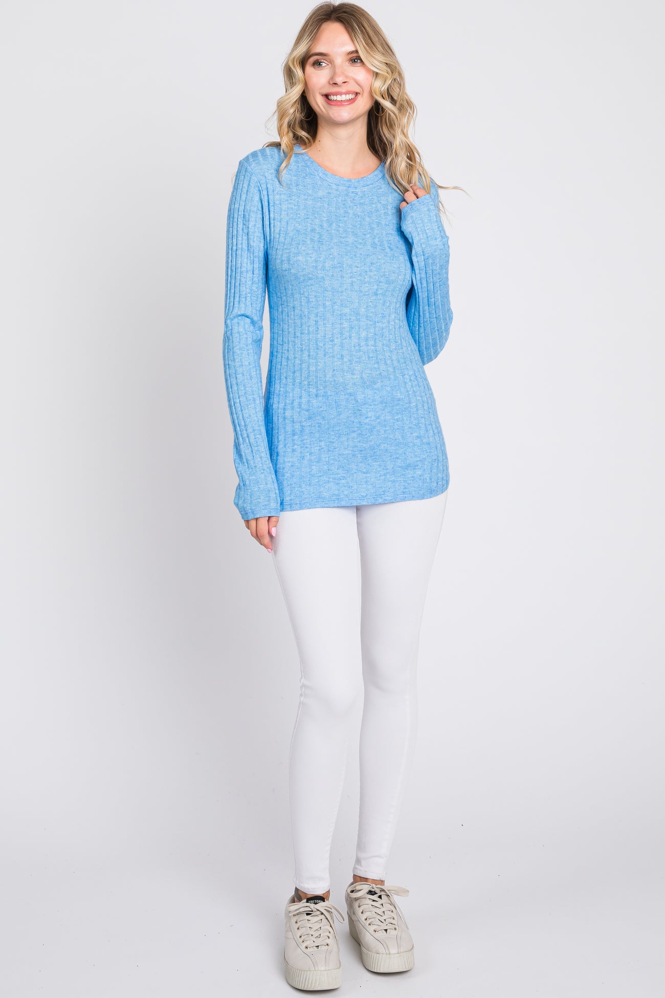 woman wearing a light blue ribbed long sleeve sweater with white skinny jeans and sneakers