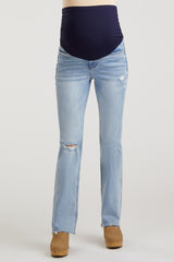 woman wearing light blue distressed maternity jeans with a dark blue supporting belly panel