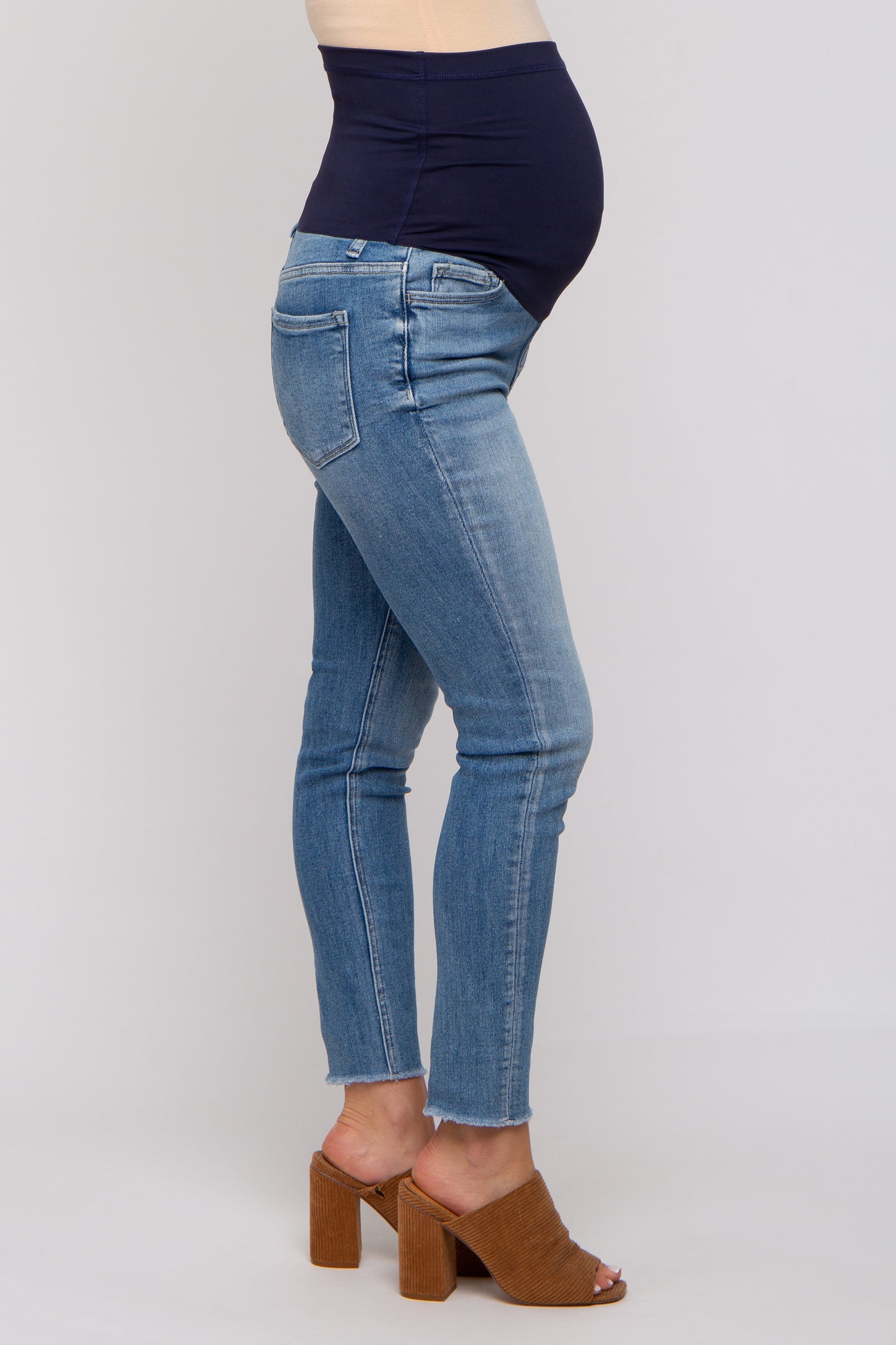 woman wearing light blue maternity jeans with a navy waistband and a visible baby bump