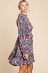 woman wearing a grey floral long sleeve dress with a ruffled hem and a fitted waist