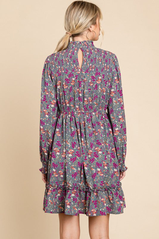 woman wearing a gray floral long sleeve dress with a ruffled hem and keyhole back detail