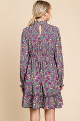 woman wearing a gray floral long sleeve dress with a ruffled hem and keyhole back detail