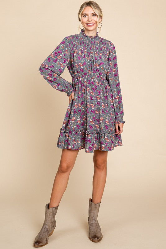 woman wearing a gray floral long sleeve dress with ruffle hem and frill details, paired with gray ankle boots