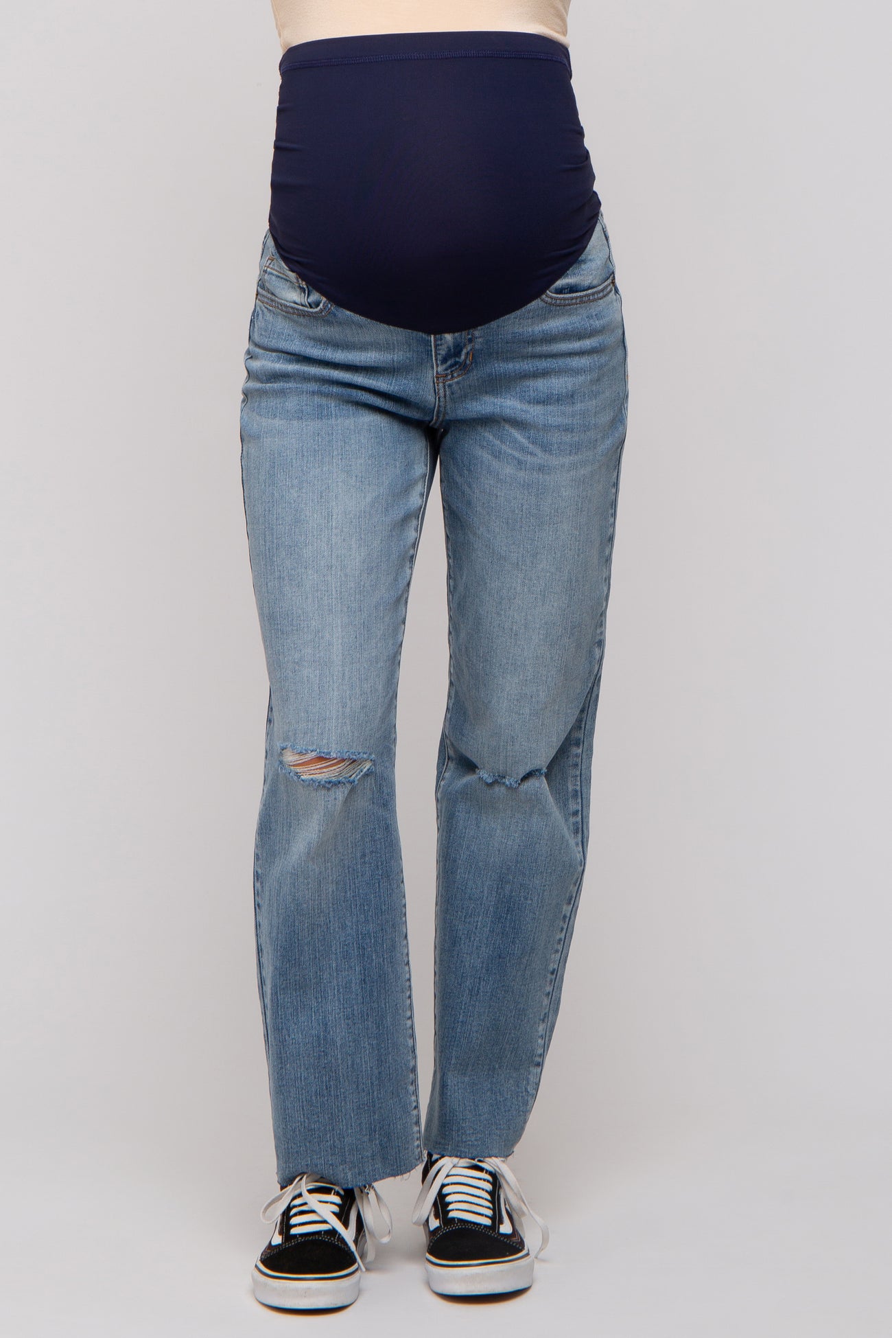 woman wearing a pair of light blue maternity jeans with a dark blue belly panel and distressed details on the front