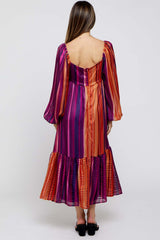 woman wearing a colorful striped maternity maxi dress with long sleeves and a tiered hem, showing off a baby bump