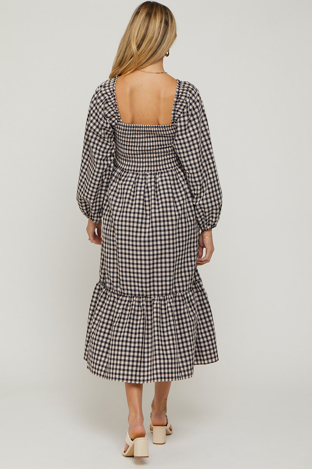 woman wearing a black and white gingham maternity dress with long puff sleeves and a tiered skirt, showing her back