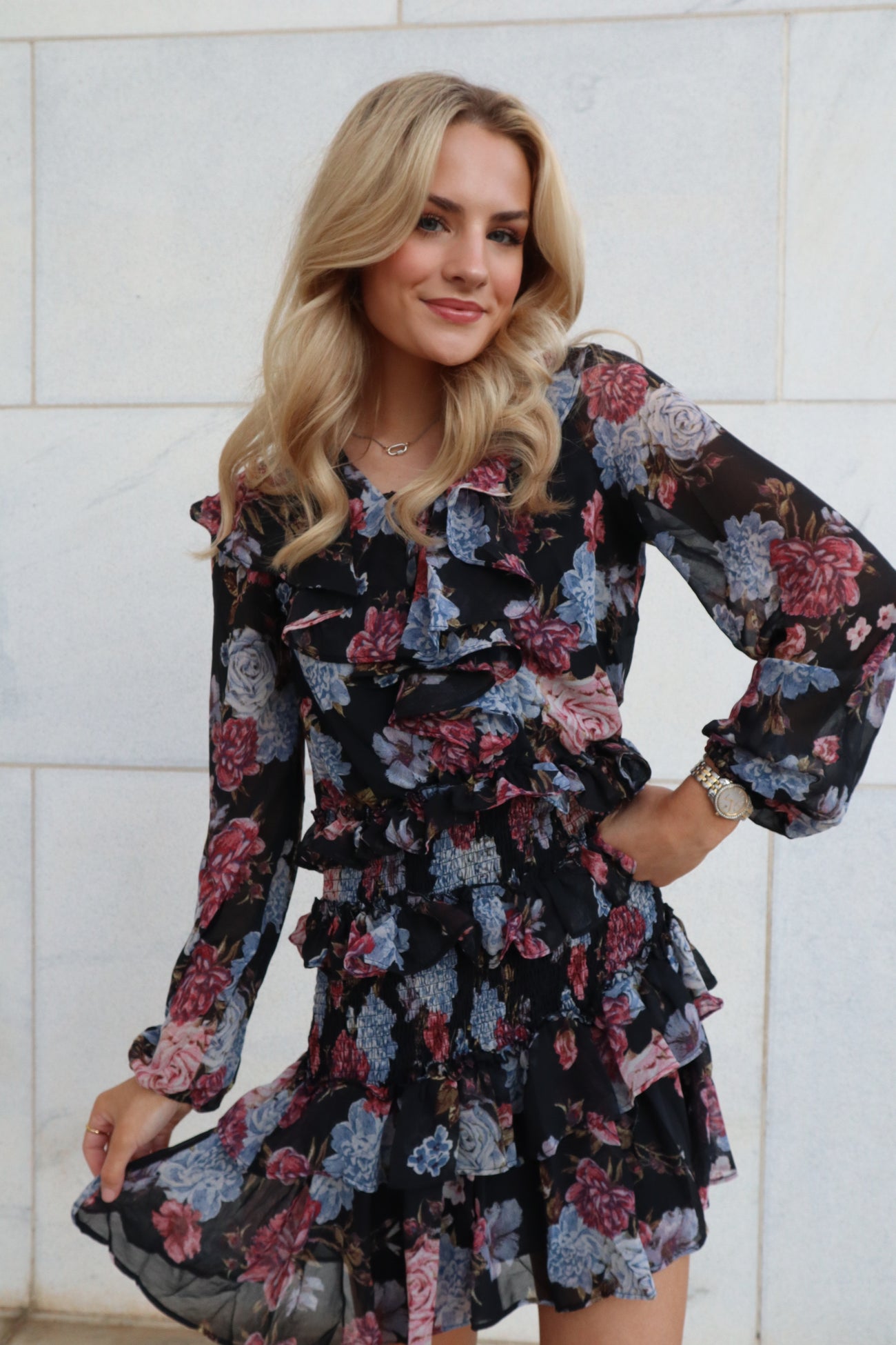 woman wearing a black floral ruffled dress with long sleeves and a tiered skirt