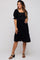 woman wearing a black maternity dress with puff sleeves and a smocked bodice, gently holding her baby bump