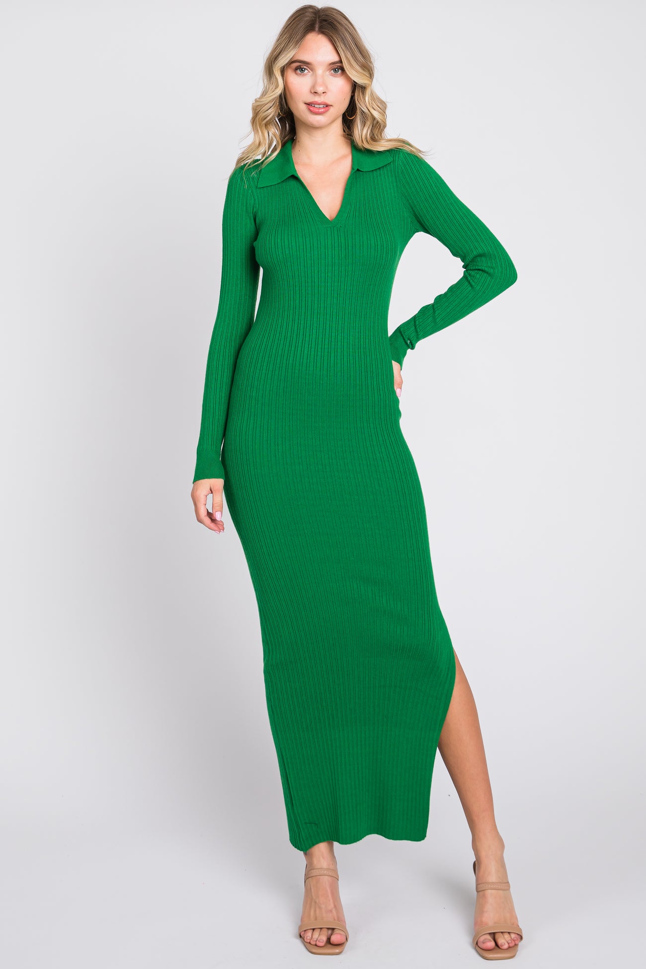 woman wearing a green ribbed maxi dress with a v-neck and long sleeves, posing with one hand on her hip