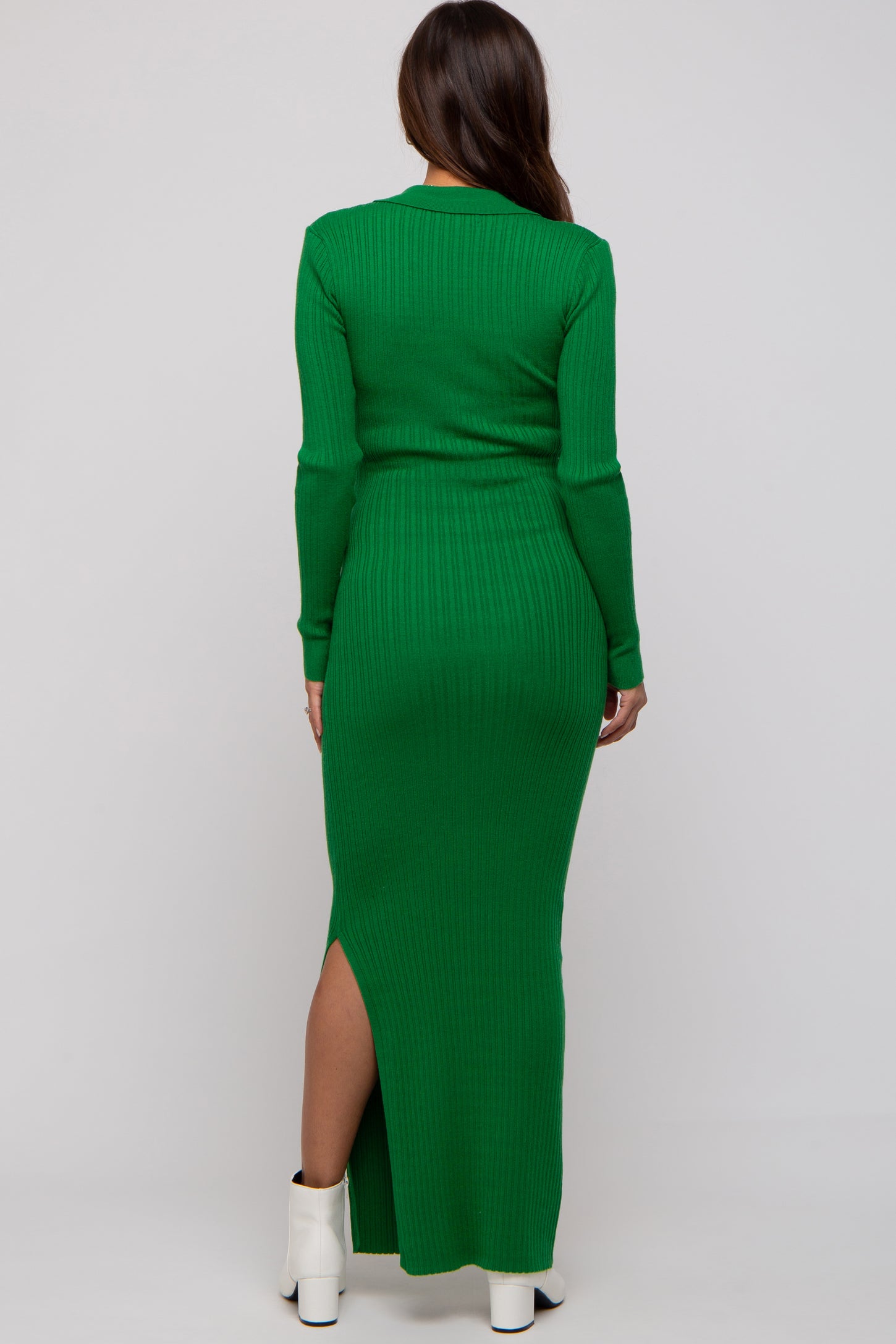 woman wearing a long sleeve green ribbed maternity dress with a side slit, showing her baby bump from the back