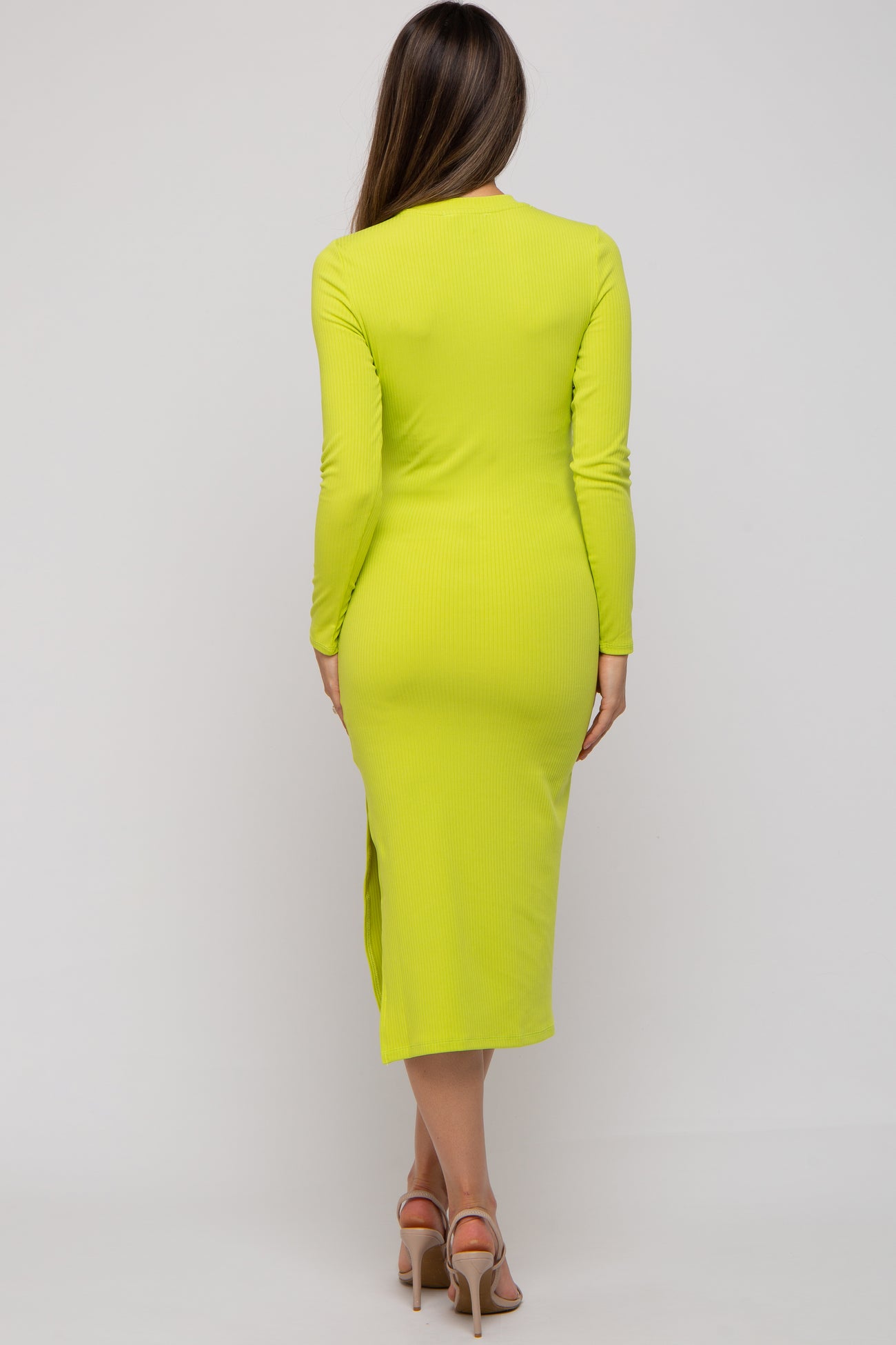 woman wearing a bright yellow long sleeve maternity dress with a knee-high side slit