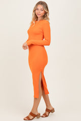woman wearing an orange long sleeve ribbed midi dress with side slits and tan heeled sandals