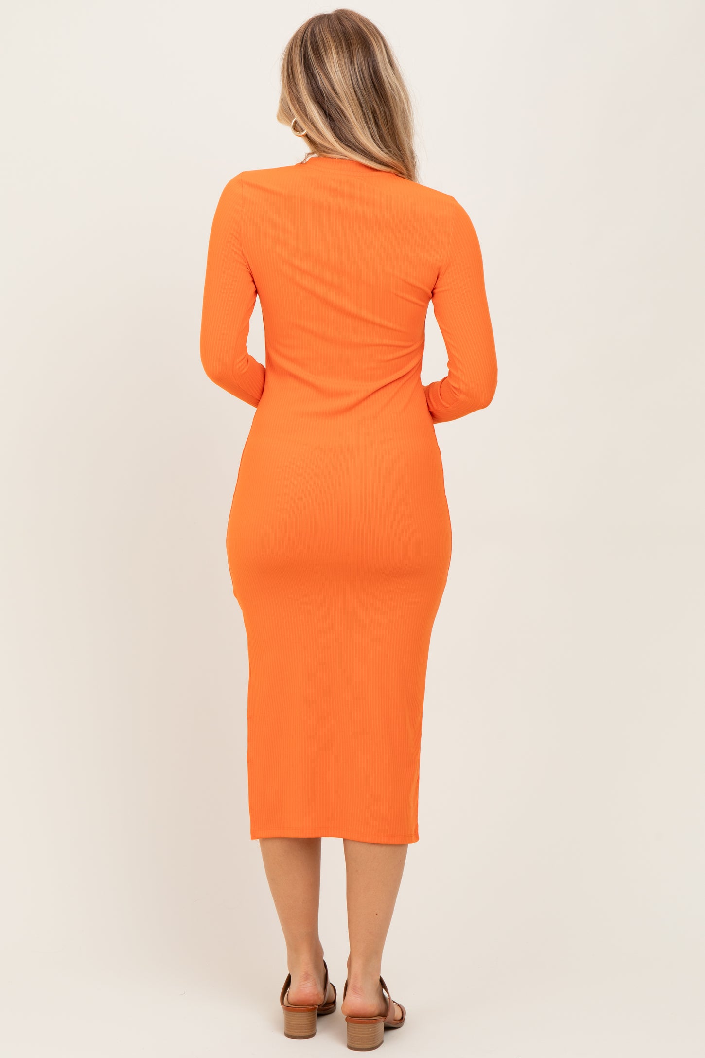 woman wearing an orange long sleeve midi dress with a fitted silhouette, viewed from the back