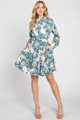 woman wearing a blue and cream floral print shirt dress with a ruffled hem and pockets