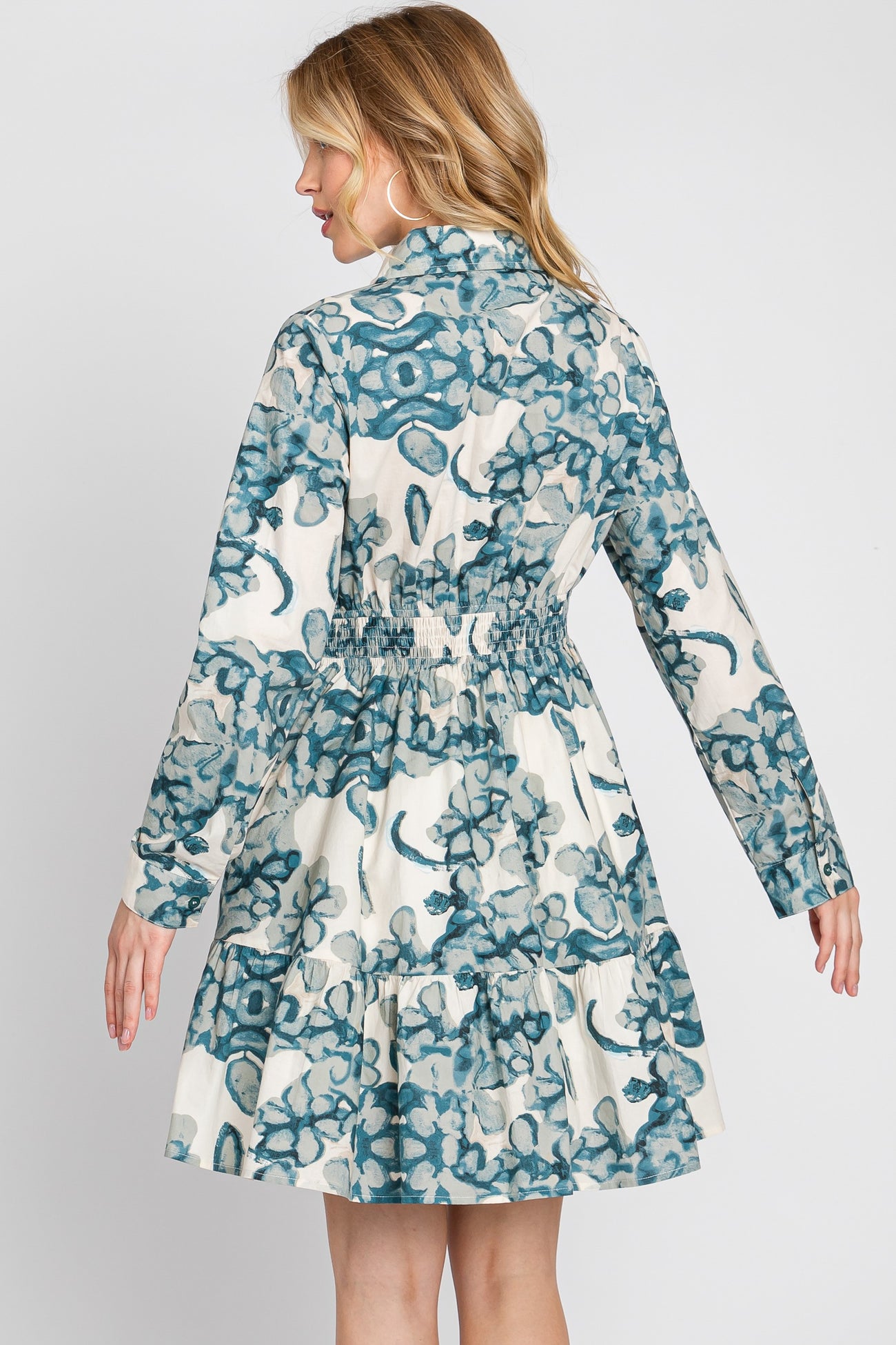woman wearing a floral print long sleeve dress with a fitted waist and tiered skirt