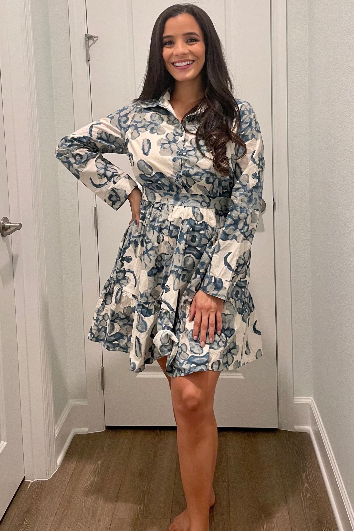 woman wearing a floral print button-up shirt dress in blue and white, posing with one hand on her hip