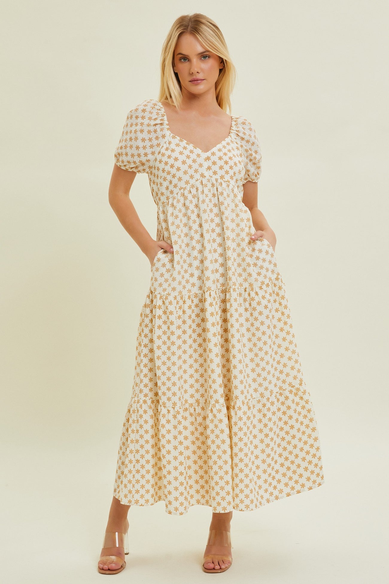woman wearing a white maxi dress with yellow floral pattern and puff sleeves, featuring side pockets