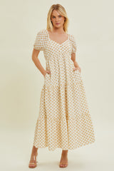 woman wearing a white maxi dress with yellow floral pattern and puff sleeves, featuring side pockets