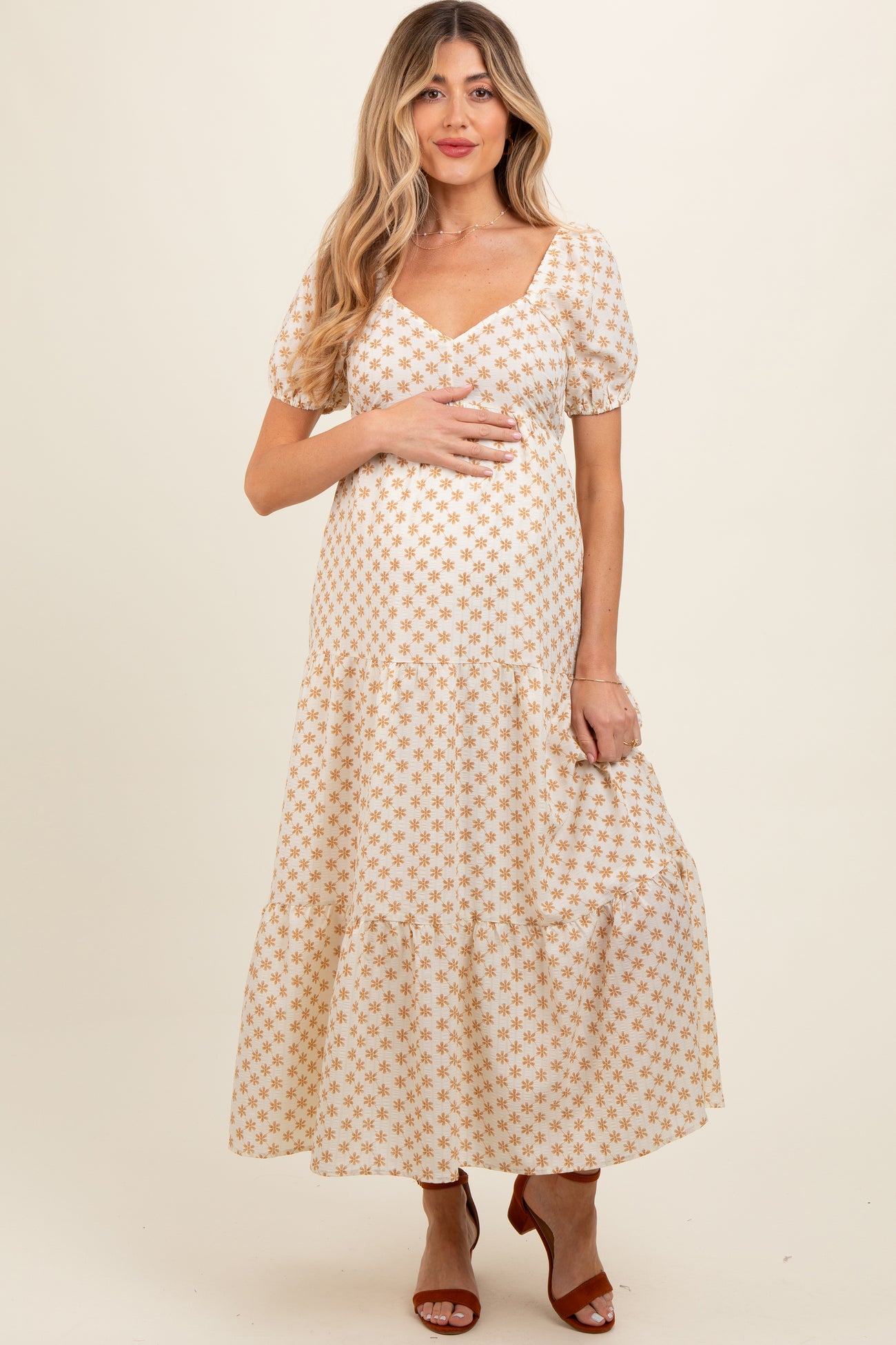 woman wearing a white floral maternity maxi dress with puff sleeves and a baby bump visible