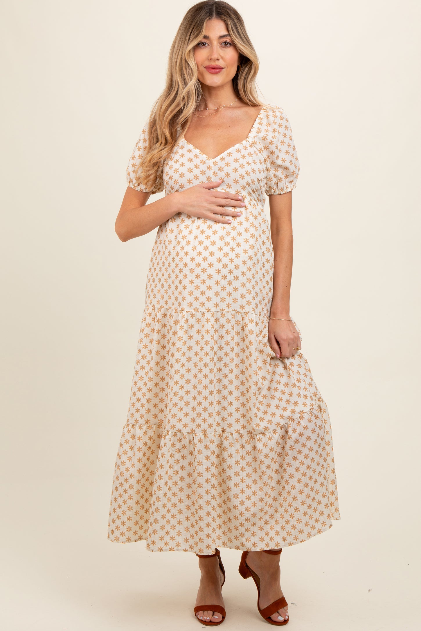 woman wearing a white floral maternity maxi dress with puff sleeves and a baby bump visible