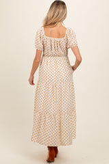 woman wearing a white maternity maxi dress with a floral pattern and puff sleeves, showing a baby bump from the back