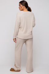 woman wearing a beige ribbed maternity loungewear set with long sleeves and wide-leg pants, showing a relaxed fit from behind