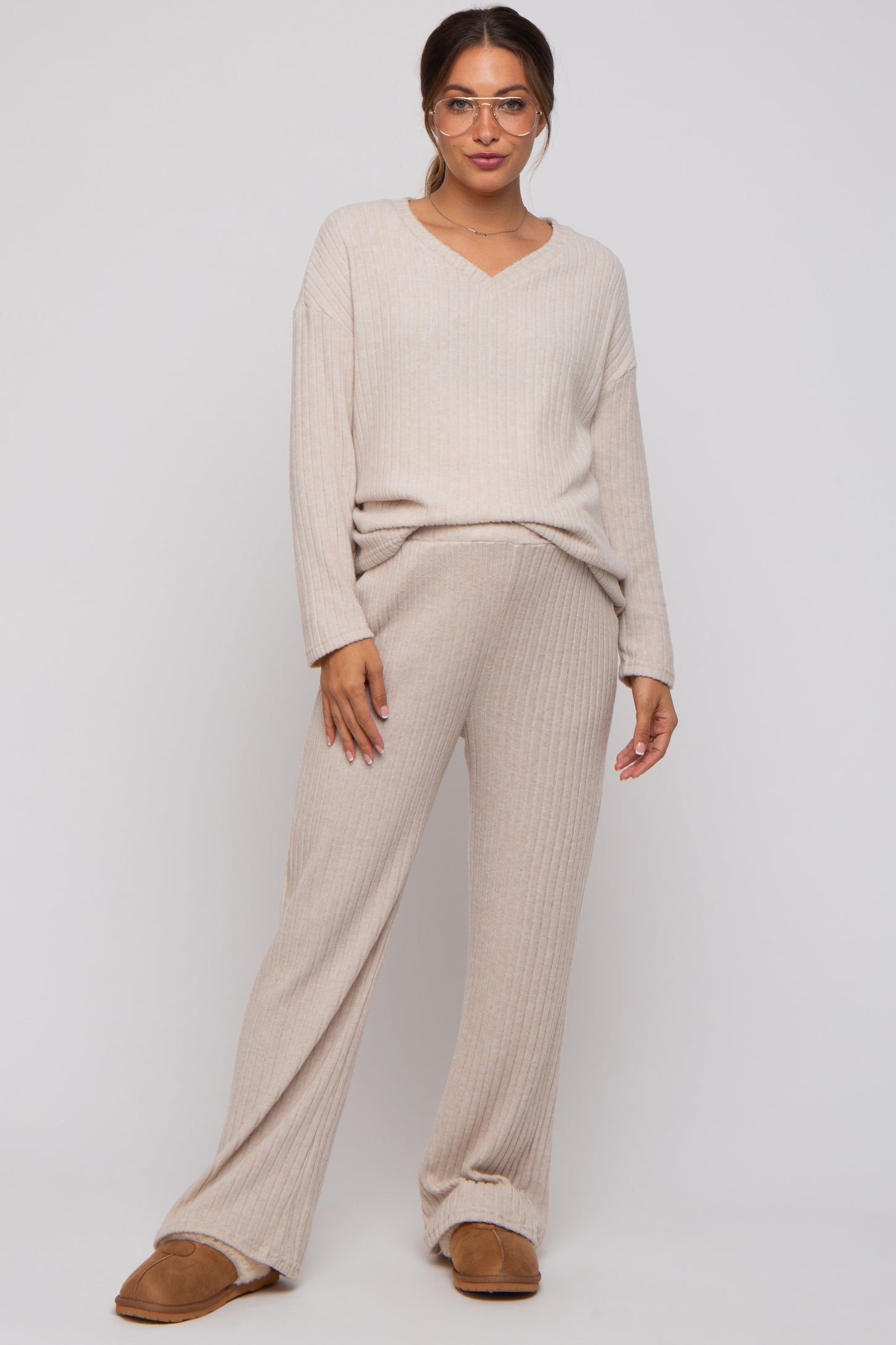 woman wearing a beige ribbed maternity sweater and matching wide-leg pants, featuring a v-neckline and relaxed fit