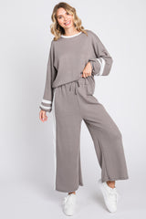 woman wearing a gray two-piece loungewear set with white stripe details and wide-leg pants