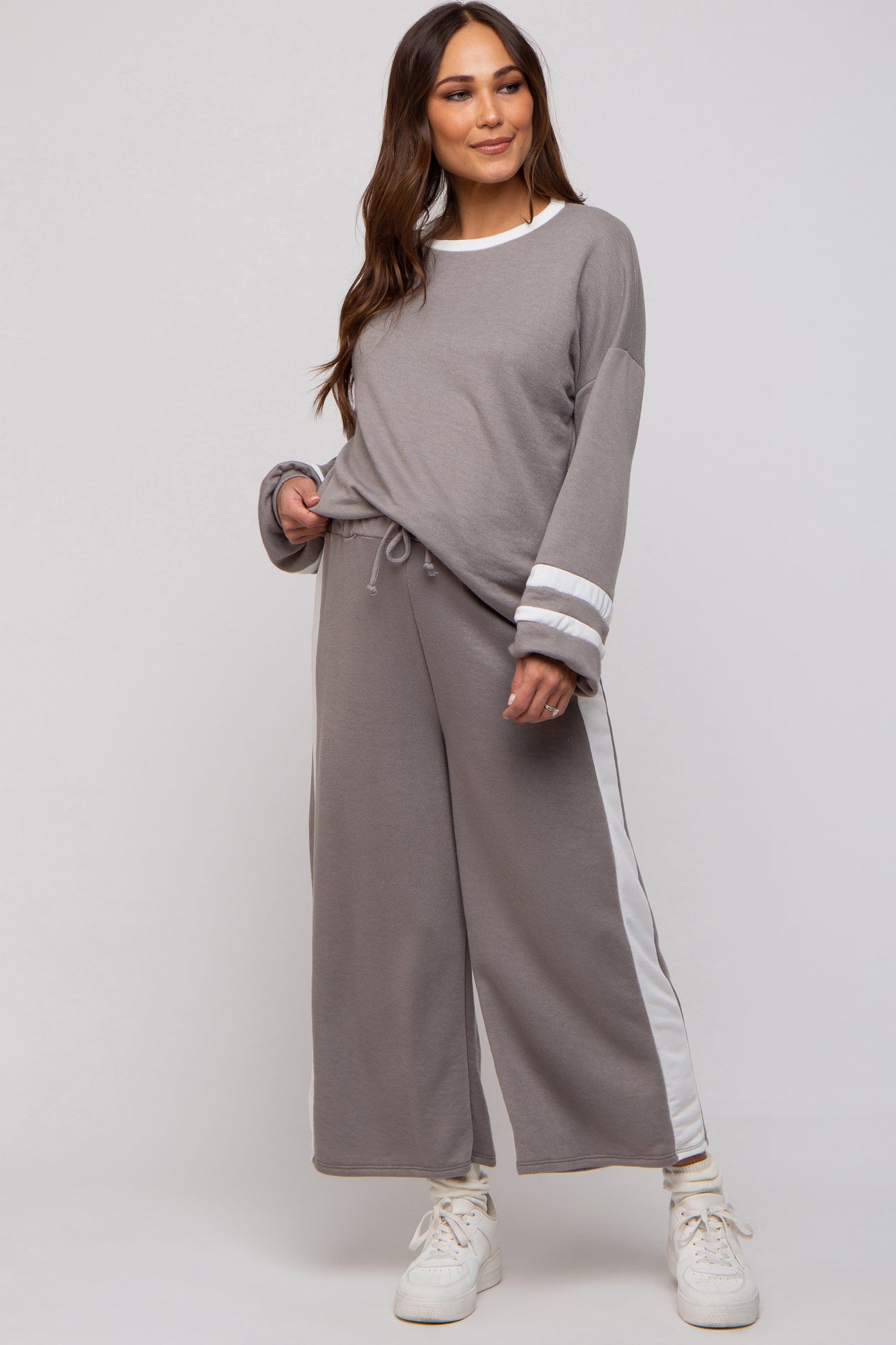 woman wearing a grey maternity loungewear set with long sleeves and wide leg pants featuring white side stripes