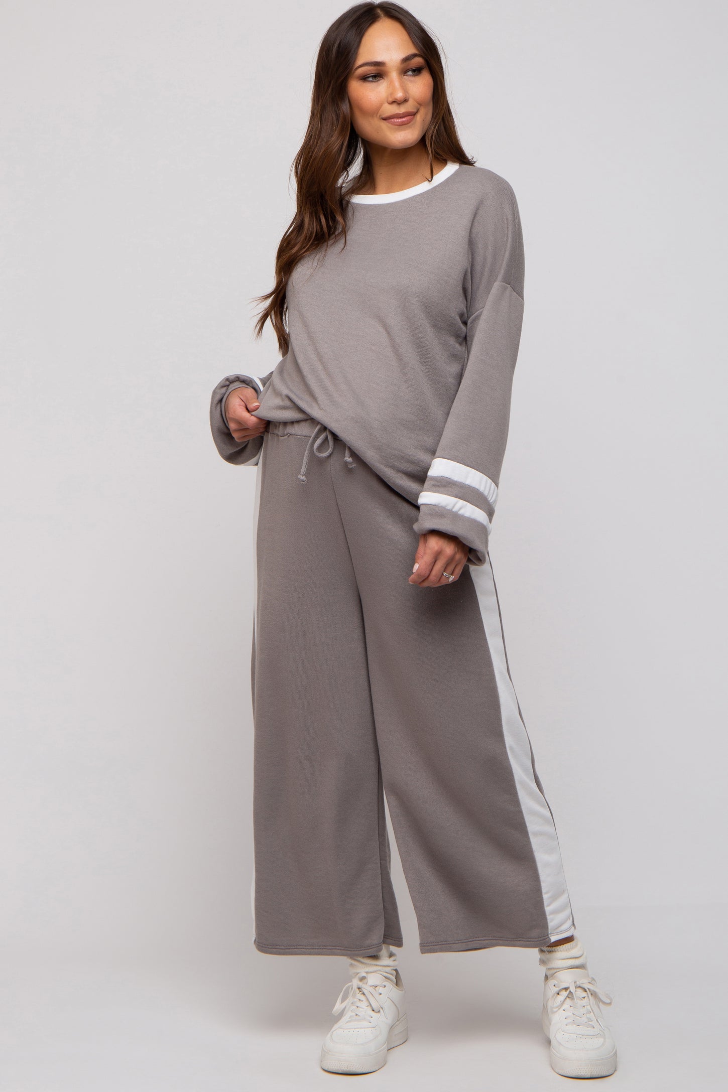 woman wearing a grey maternity loungewear set with long sleeves and wide leg pants featuring white side stripes