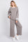 woman wearing a gray relaxed fit sweater and matching wide leg pants with white stripes, styled with white sneakers