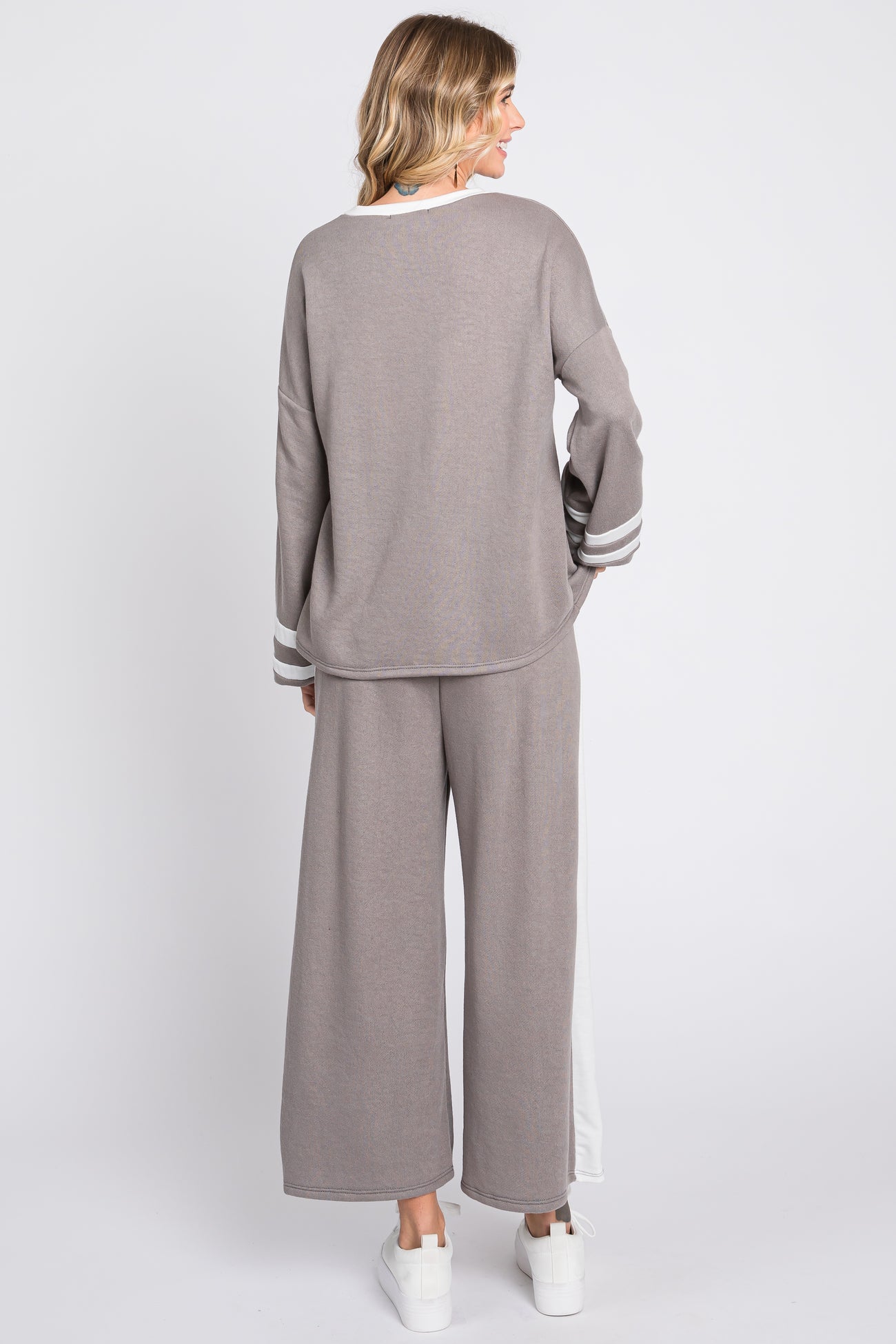 woman wearing a gray long sleeve top with stripes and wide leg pants, viewed from the back