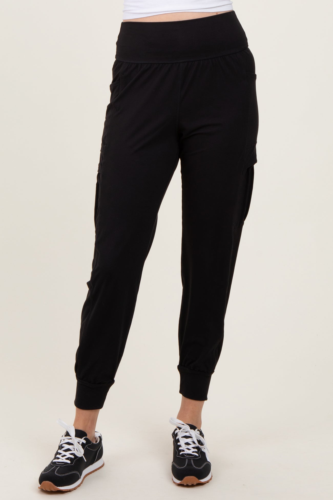 woman wearing black jogger pants with side pockets and cuffed ankles, paired with black sneakers