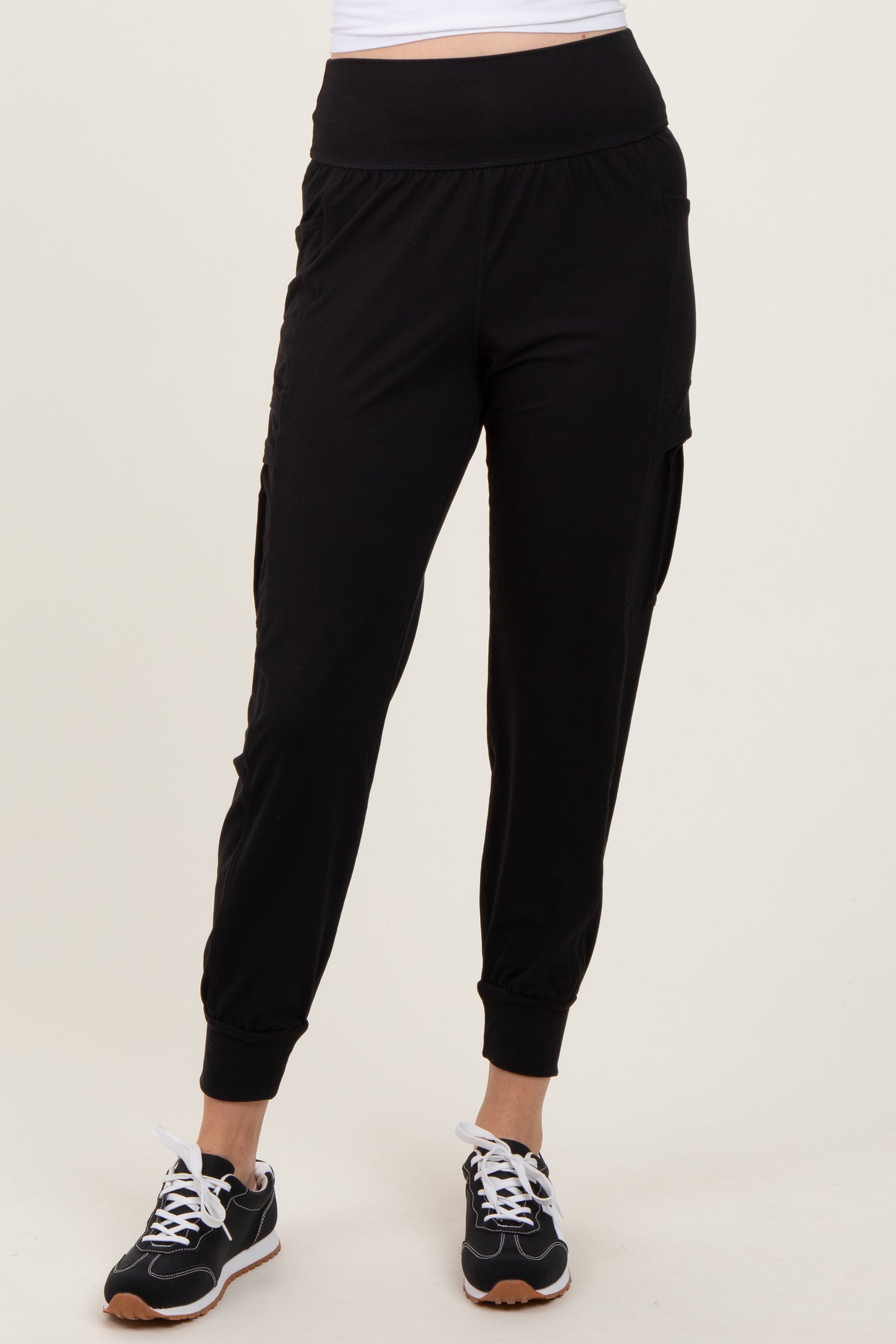 woman wearing black jogger pants with side pockets and cuffed ankles, paired with black sneakers