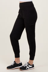 woman wearing black jogger pants with a high waistband and side pocket, paired with black and white sneakers