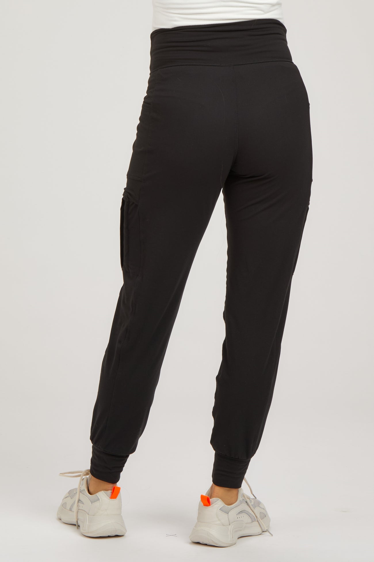 woman wearing black maternity jogger pants with a high waistband and side pockets, paired with white sneakers