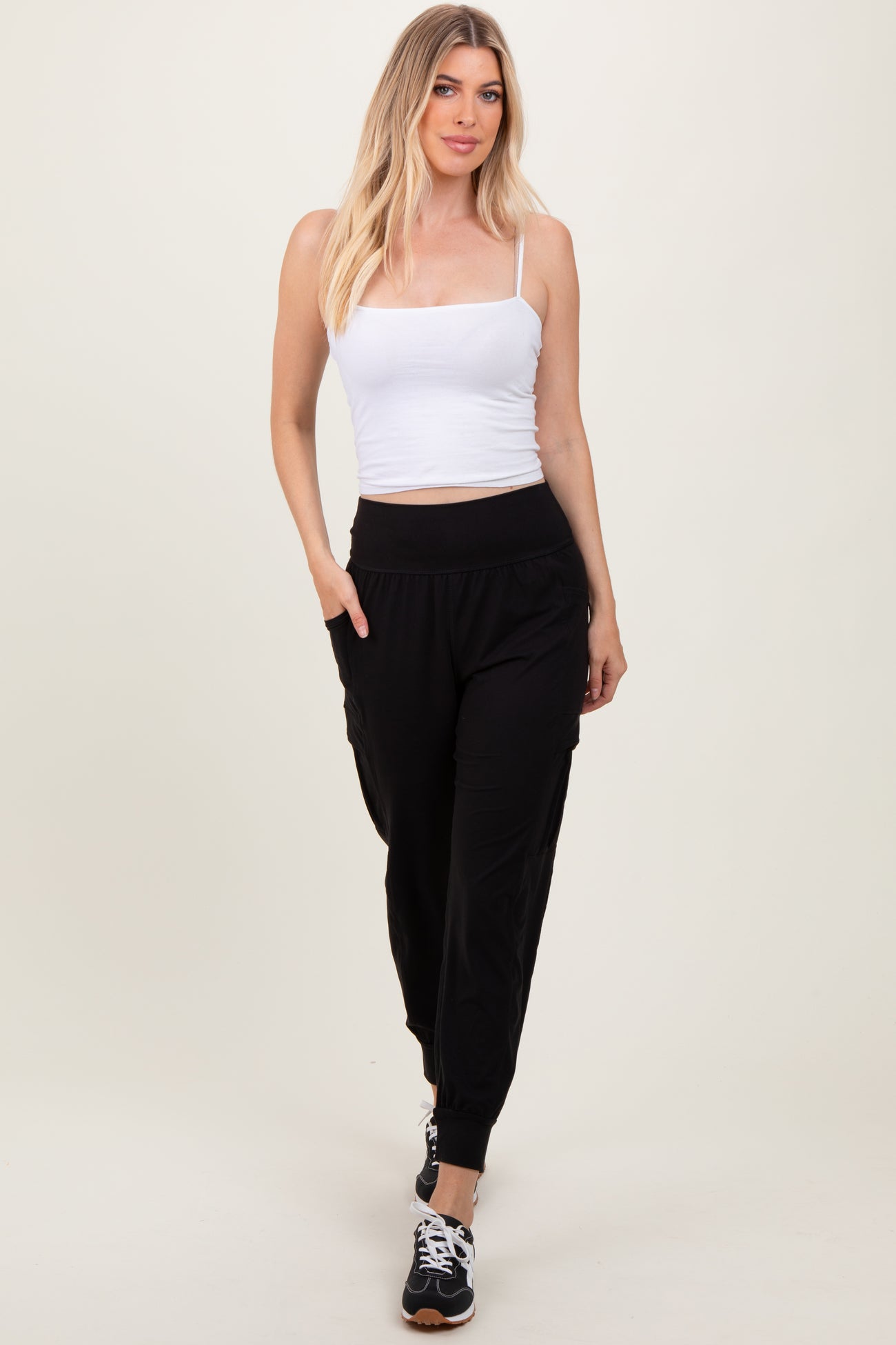woman wearing a white fitted crop top and black tapered jogger pants with side pockets and cuffed ankles