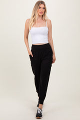 woman wearing a white fitted crop top and black tapered jogger pants with side pockets and cuffed ankles