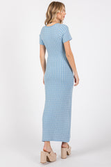 woman wearing a light blue ribbed maxi dress with short sleeves and a fitted silhouette, standing with her back to the camera