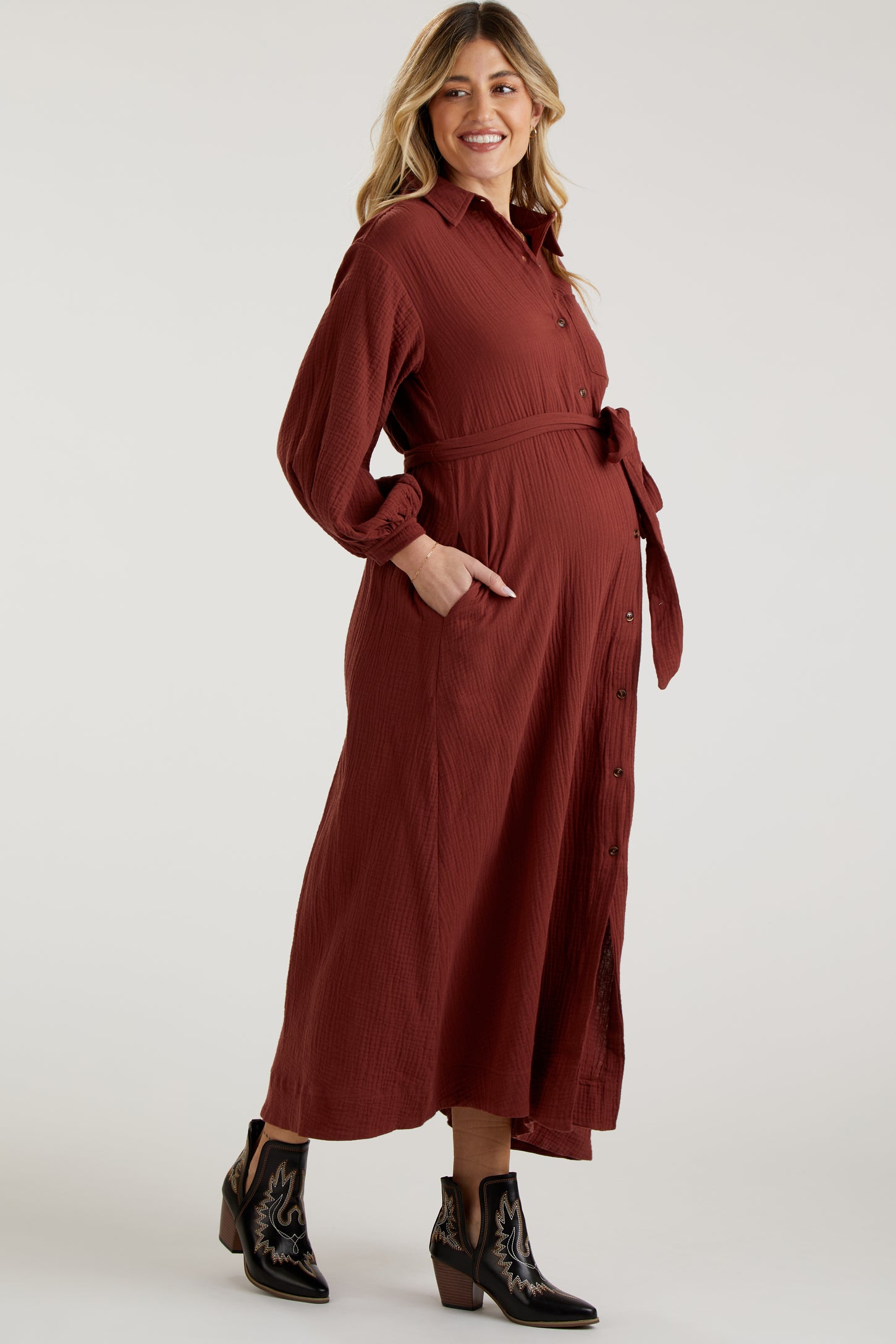 woman wearing a rust-colored long sleeve maternity dress with a belted waist and a visible baby bump