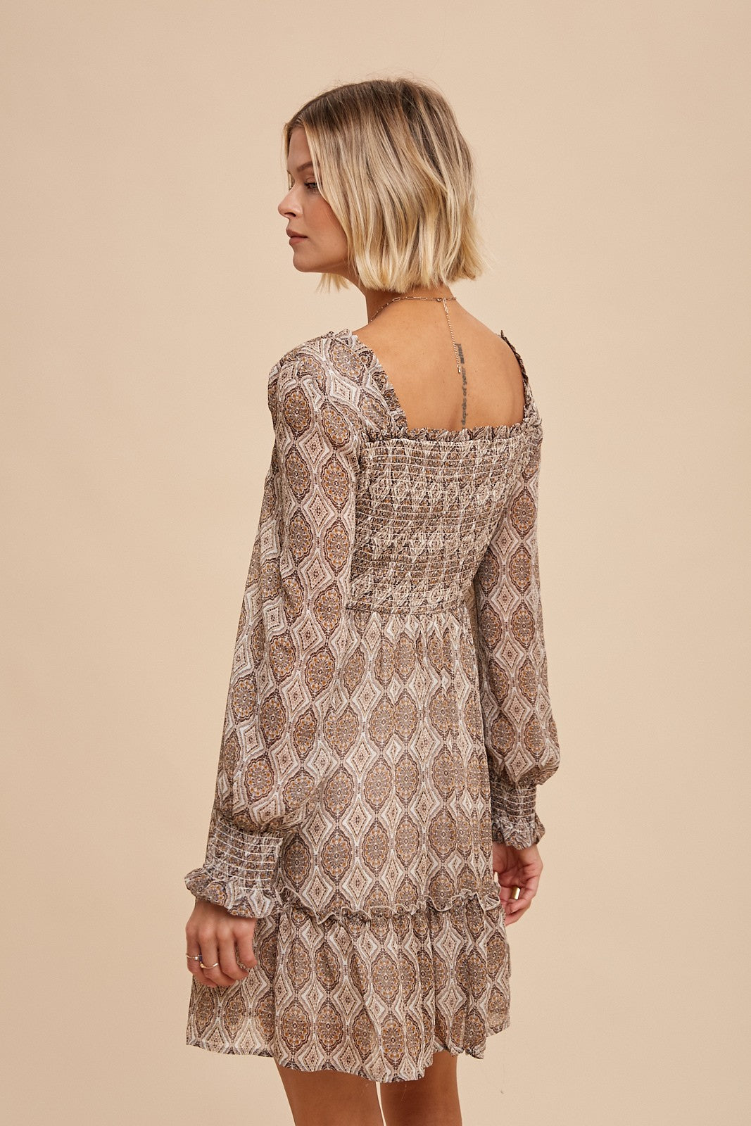 woman wearing a bohemian-style brown patterned mini dress with a smocked bodice and puff sleeves