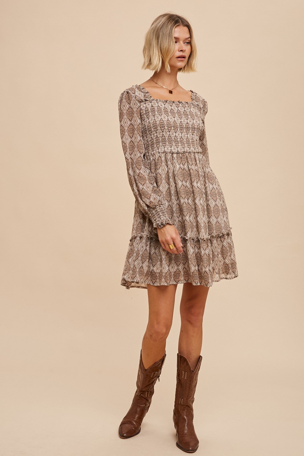 woman wearing a brown patterned long sleeve mini dress with ruffles and cowboy boots