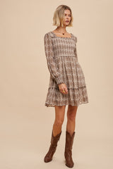 woman wearing a brown patterned long sleeve mini dress with ruffles and cowboy boots